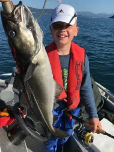Familienurlaub Norwegen – Kind mit Seelachs auf Boot
